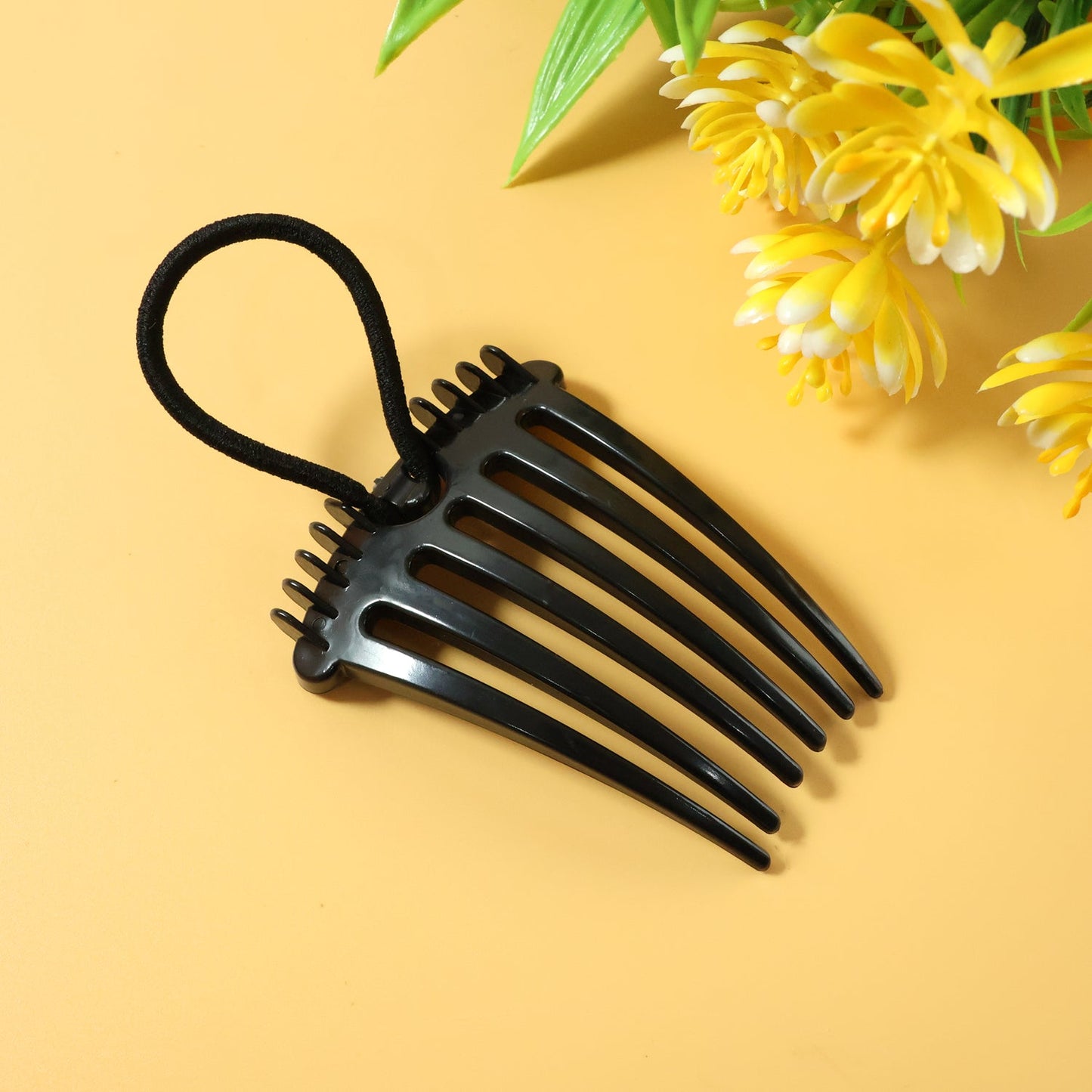 Close up of volumizing hair bun comb clip with elastic loop for secure styling