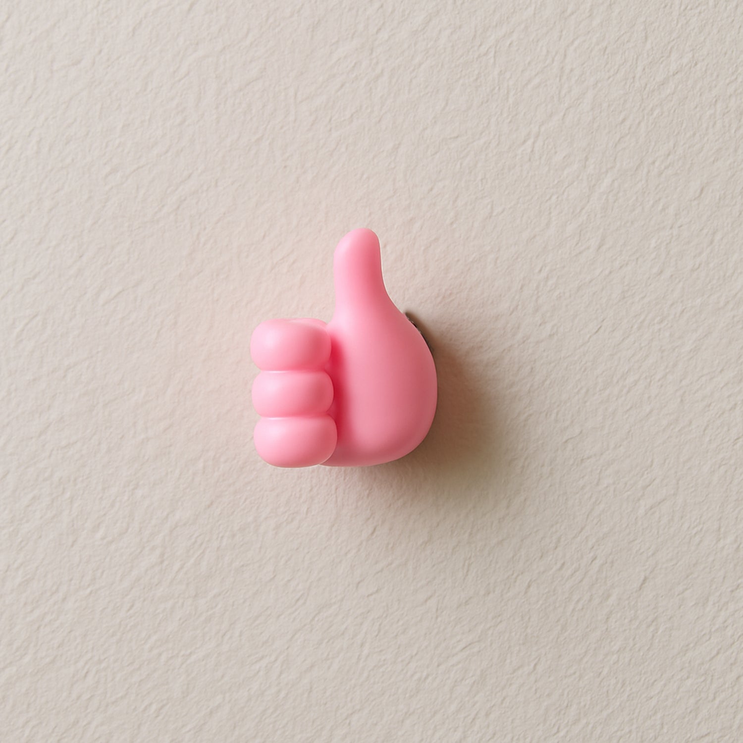 Pink hand-shaped wall clip holder made of silicone on white background