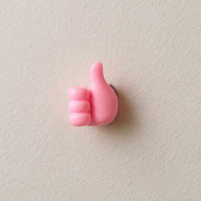 Pink hand-shaped wall clip holder made of silicone on white background