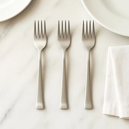 Stainless steel dining forks arranged on a table, ready for a meal setting.