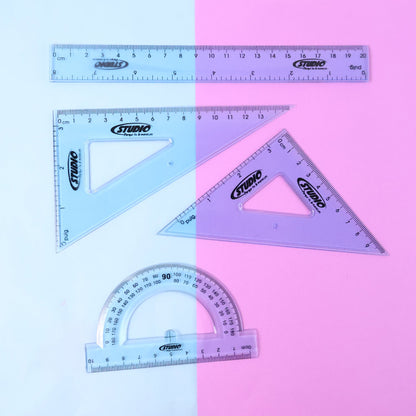 Transparent geometry tools laid out on surface showing ruler, protractor and set squares