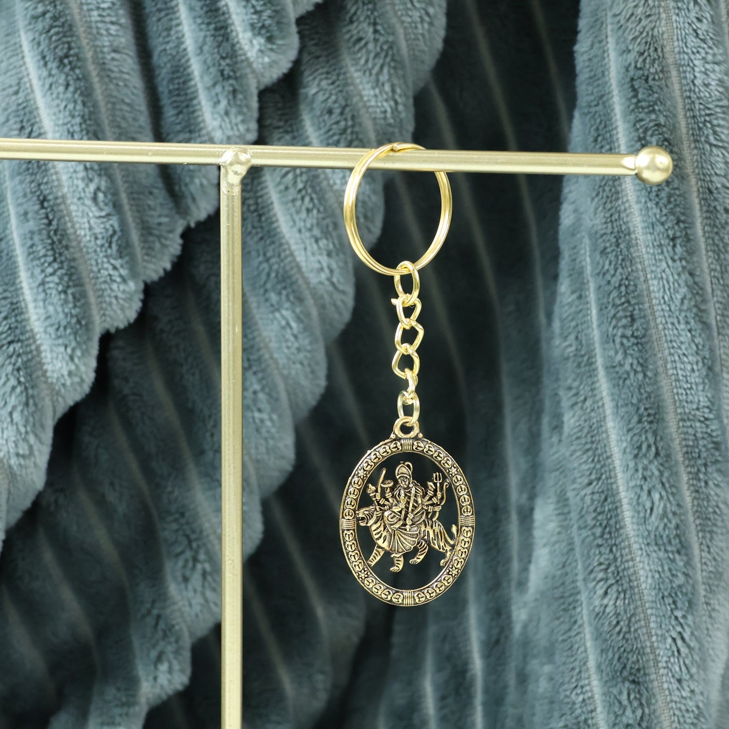 Hand holding the Maa Durga golden oval frame metal keychain