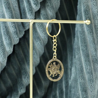 Hand holding the Maa Durga golden oval frame metal keychain