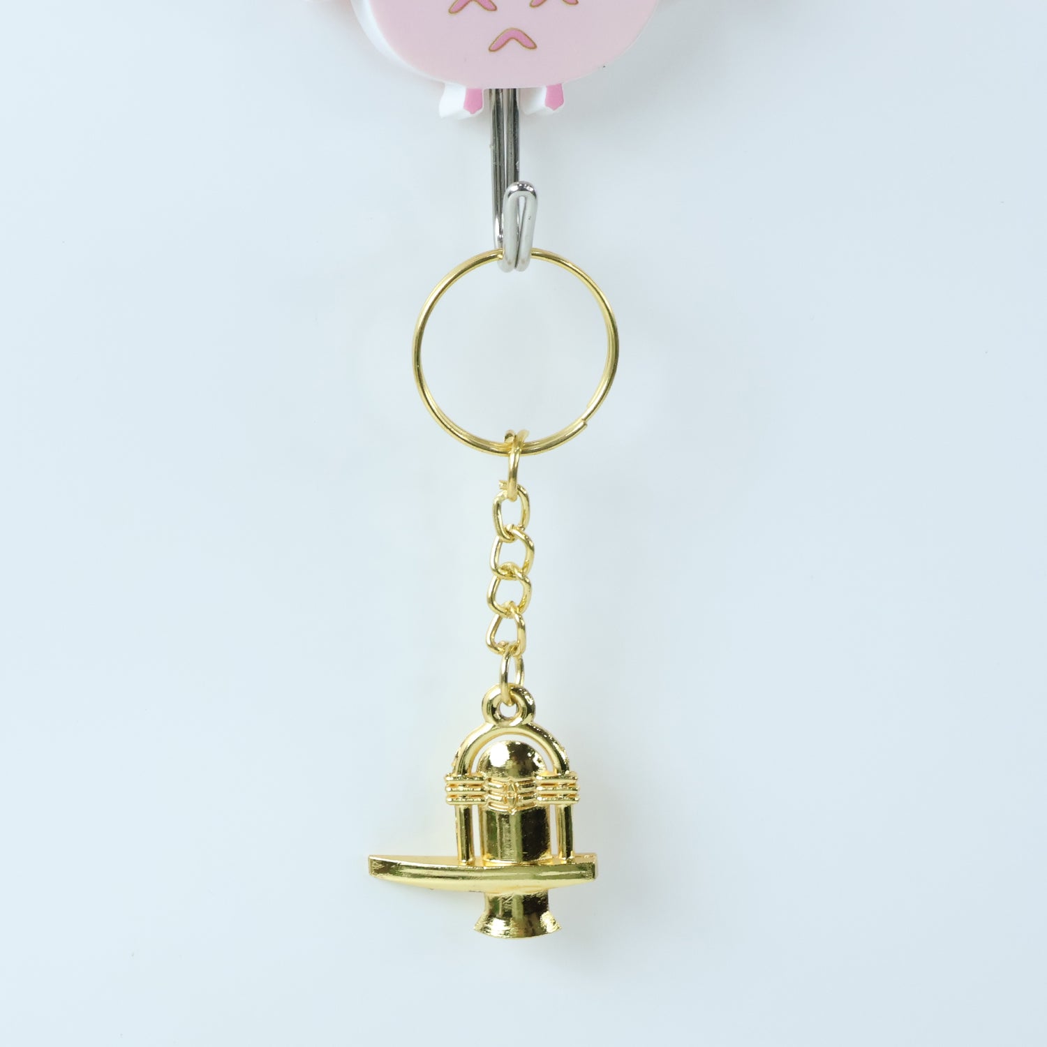 Golden Shivling metal keychain resting on a flat surface highlighting golden finish