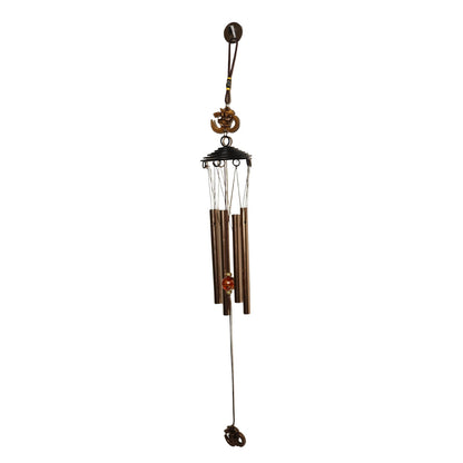 Side view of metal wind chime with Om symbol against green background