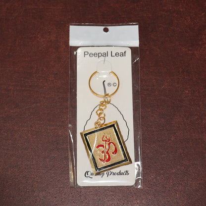 Om Trishul symbol keychain resting on surface, showcasing design and metal material