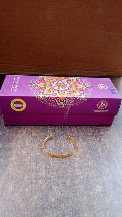 Close-up detail of gold finish open cuff bracelet Kada material and finish