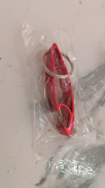 Portable metal bottle opener keychain next to keys on table