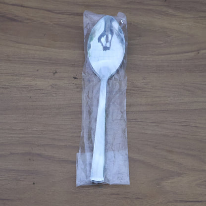 Stacked stainless steel dining spoons placed in a home kitchen setting