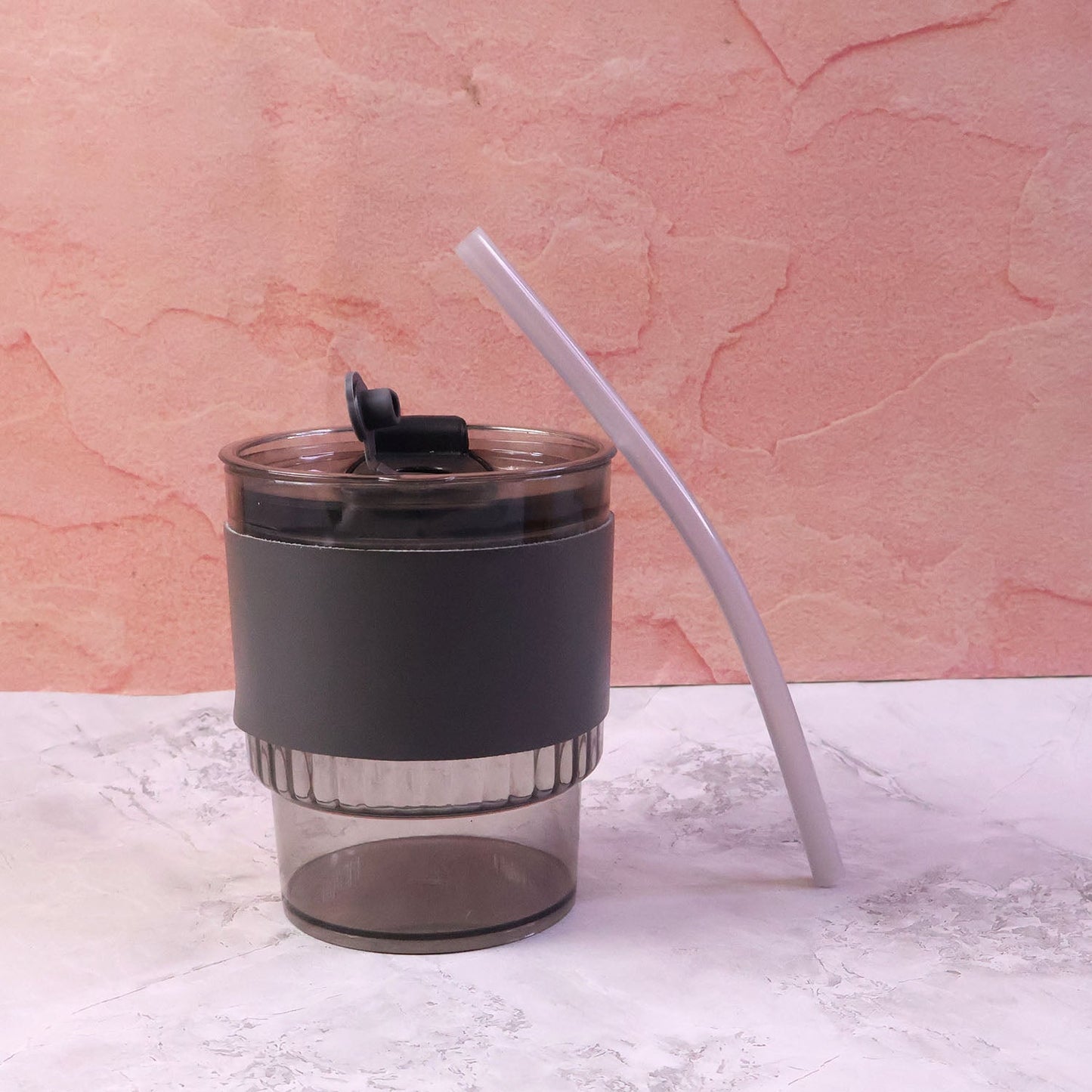 Stylish plastic tumbler with lid and straw, designed for easy portability.